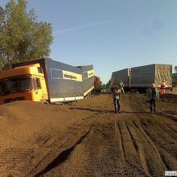 Dwie ciężarówki brały udział w wypadku drogowym na polnej drodze w okolicach Trzebnicy, a funkcjonariusze i pomoc drogowa oceniali sytuację.