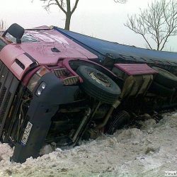 Przewrócona półciężarówka leżąca na boku na śniegu po wypadku drogowym, oczekująca na pomoc drogową do holowania.
