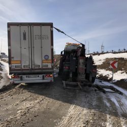 Laweta wyciąga ciężarówkę z błotnistym nasypem na zaśnieżonej drodze w pobliżu Trzebnicy.