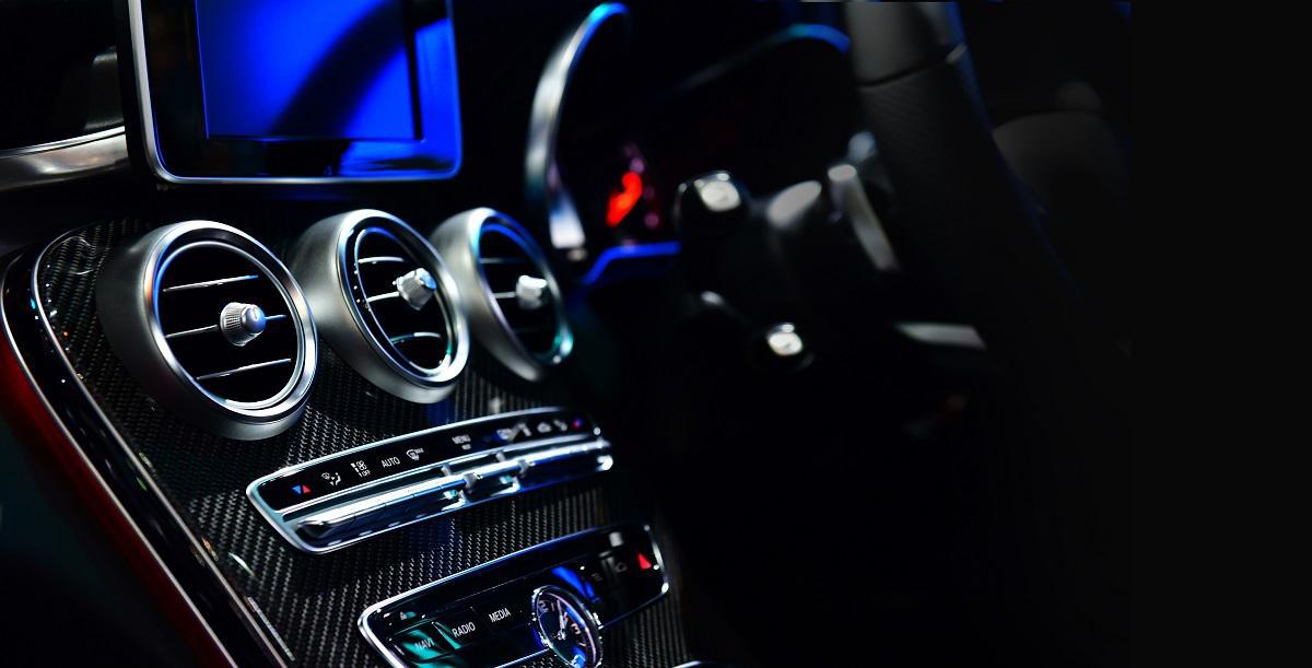 Eleganckie i nowoczesne wnętrze samochodu nocą, wyposażone w podświetlane elementy sterujące, ekran dotykowy, luksusowe akcenty z włókna węglowego